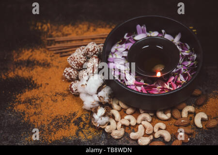 Schüssel mit brennenden Kerze und Blüten für die Feier des Divaly auf dunklem Hintergrund Stockfoto