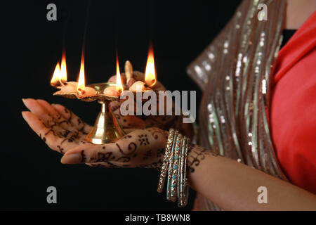 Schöne Frau mit diya Lampe für die Feier des Divaly auf dunklem Hintergrund, Nahaufnahme Stockfoto