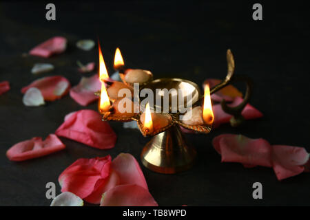 Diya Lampe mit Blütenblättern für die Feier des Divaly auf dunklem Hintergrund Stockfoto