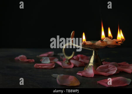 Diya Lampe mit Blütenblättern für die Feier des Divaly auf dunklem Hintergrund Stockfoto