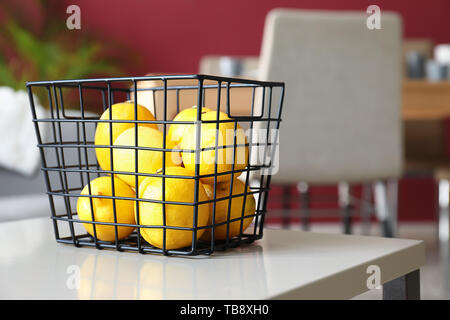 Korb mit frischen Zitronen auf Tisch im Zimmer Stockfoto