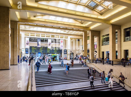 Passagiere warten oder zu Fuß die Treppen hoch und runter unter dem Glasdach in der Bahnhofshalle des Brüsseler Hauptbahnhof. Stockfoto