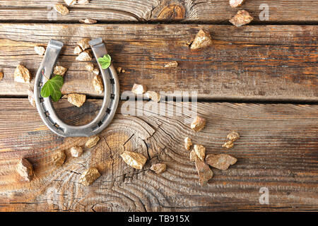 Komposition mit Hufeisen, golden Nuggets und Klee für St. Patrick's Day auf hölzernen Hintergrund Stockfoto