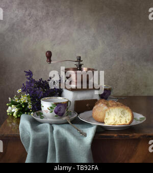 Retro still life Poster Frühstück. Vintage Kaffeemühle Tassen, silbernen Löffel, hausgemachtes Brot Bäckerei. Dark Light, Holztisch, Bettwäsche aus Geweben Stockfoto