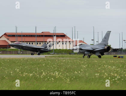 Eine F-35A Lightning II landet während einer F-16C Fighting Falcon wartet bei Aviano Air Base, Italien, 29. Mai 2019 zu nehmen. Die 388 Fighter Wing und Reserve 419th Fighter Wing, sind in Europa die Teilnahme an einer Theater Sicherheitspaket, Durchführung von Übungen und Schulungen mit anderen Europa-basierten Flugzeuge. (U.S. Air Force Foto von älteren Flieger Heidi Goodsell) Stockfoto