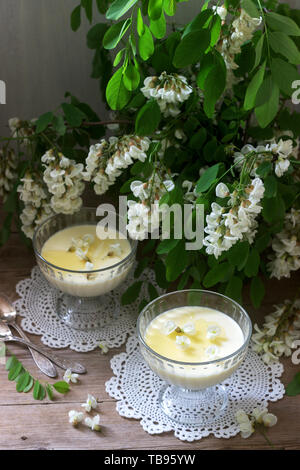 Panna cotta mit robinie Geschmack, serviert mit Honig und weißen Robinie Blumen. Im rustikalen Stil. Stockfoto