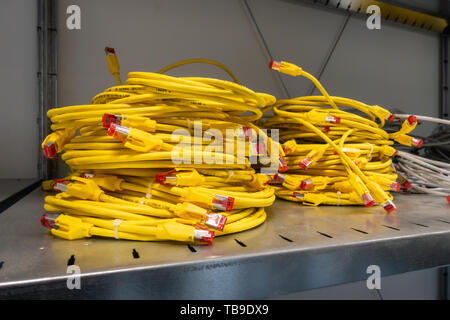 Leuchtend gelben Ethernet Kabel aufgewickelt und gestapelt in Storage Rack Server Zimmer Stockfoto