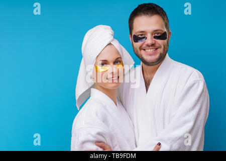 Foto von Mann und Frau mit Gel Pads unter den Augen und in der weißen Robe Stockfoto