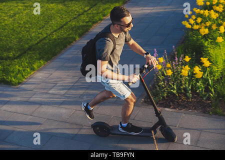 Attraktiver Mann, elektrische Kick scooter am wunderschönen Parklandschaft. Ansicht von oben. Stockfoto