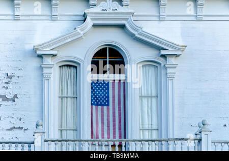 Eine amerikanische Flagge hängt im Fenster eines historischen antebellum Home in die Seventh Street North in der Innenstadt von Columbus, Mississippi. Stockfoto