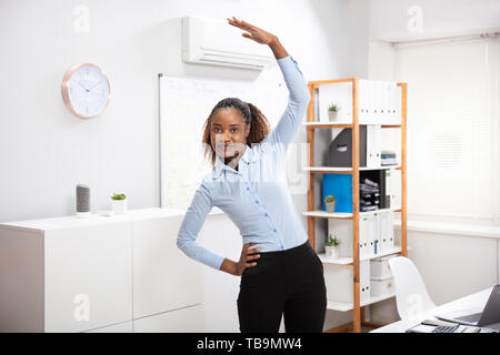 Junge Geschäftsfrau Yoga Vor Büro Schreibtisch Stockfoto