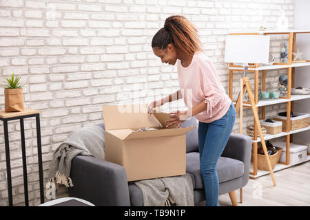 Glückliche Frau Öffnen der Paketbox zu Hause Stockfoto