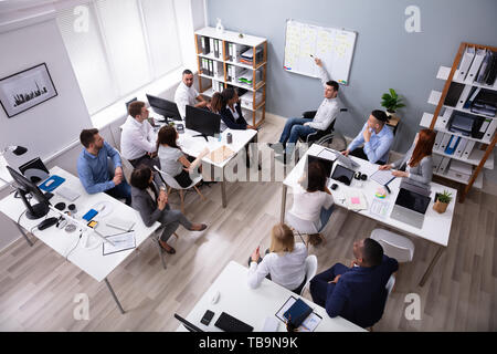 Behinderte junge Geschäftsmann auf Rollstuhl eine Präsentation halten zu seinen Kollegen im Büro Stockfoto