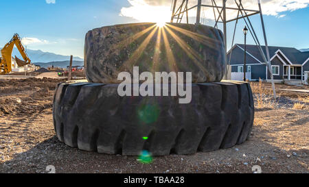 Panorama Sonne in den bewölkten Himmel hell leuchtendes hinter einem Stapel der alten Gummireifen Stockfoto