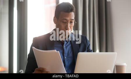 Verwirrt schwarze männliche Mitarbeiter unsicher fühlen lesen Schreibarbeit Dokumente Stockfoto