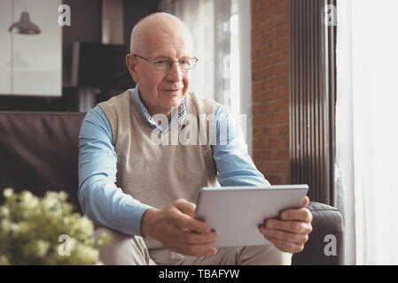 Älterer Mann mit Tablet-PC. Senior sitzen auf einem Sofa im Wohnzimmer. Stockfoto