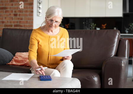 Ältere Frau mit Taschenrechner und Rechnungen zu zählen. Finanzen, Einsparungen Konzept Stockfoto