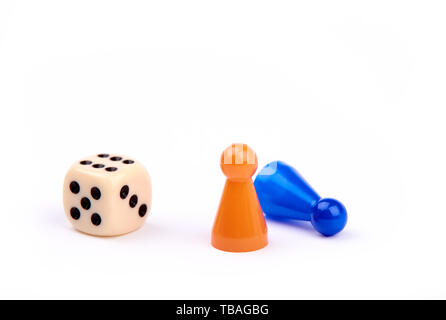 Spielen Würfel mit schwarzen Punkten und Nummer sechs, zwei Spielsteine, orange stehend als Sieger und Blau liegen als Verlierer - auf weißem Hintergrund Stockfoto