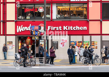 Tokyo, Japan - 30. März 2019: Shinjuku Straße Gehweg mit vielen Menschen in der Nähe von Wendy's Fast Food Restaurant mit Zeichen für erste Küche Stockfoto