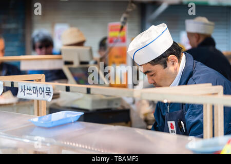 Tokyo, Japan - 30. März 2019: Äußere Market Street in Tsukiji in der Nähe von Ginza mit Anbieter mann Nahaufnahme kochen Essen zubereiten Stockfoto