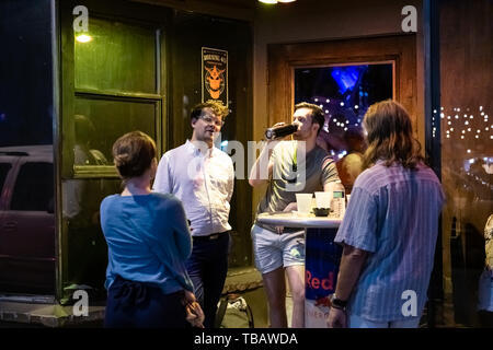 New Orleans, USA - 22. April 2018: Altstadt Frenchmen Street in Louisiana berühmten Stadt Stadt Nachtleben und Leute Gruppe von Freunden trinken sprechen in b Stockfoto