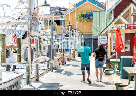 Destin, USA - 24. April 2018: Stadt Stadt Harborwalk village Promenade am Yachthafen mit Margaritaville Restaurant Paar auf Sommertag in Florida Stockfoto