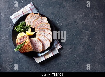 Geschnetzeltes Hähnchen Hackbraten serviert auf einem schwarze Platte mit Zitronenscheiben und frischem Thymian auf einer konkreten Tabelle, von oben betrachten, flatlay, kopieren Raum Stockfoto