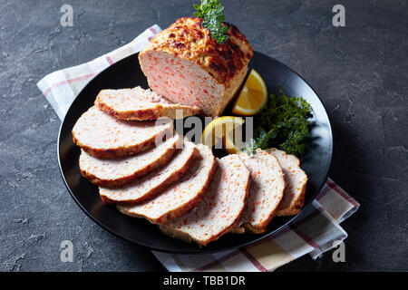 Close-up von geschnittenen Hähnchen Hackbraten auf eine schwarze Platte mit Zitronenscheiben und frischem Thymian auf einen konkreten Tisch serviert, horizontale Ansicht von oben Stockfoto