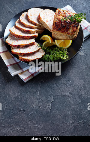 Geschnetzeltes Hähnchen Hackbraten serviert auf einem schwarze Platte mit Zitronenscheiben und frischem Thymian auf einer konkreten Tabelle, vertikale Ansicht von oben, Kopie Raum Stockfoto