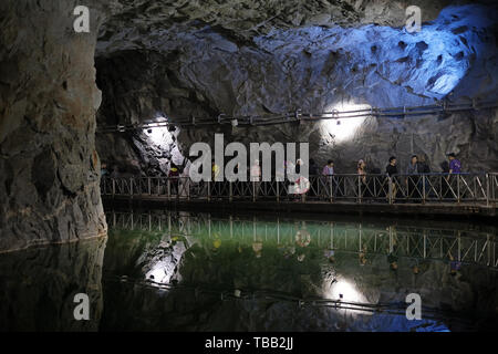 Besucher gehen in den Zhaishan Tunnel Shelter, ein größtenteils fertiggestelltes Schutzhaus, das 1961 erbaut und 1966 aus einem einzigen Stück Granitgneis für Militärboote fertiggestellt wurde. heute eine Touristenattraktion im Südosten des Gugang Lake an der nordwestlichen Küste des Kinmen County oder der Insel in Taiwan, nur wenige Kilometer vom chinesischen Festland entfernt. Stockfoto