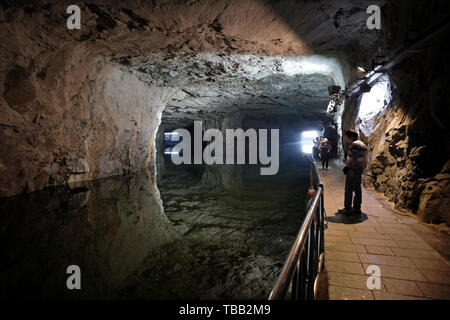 Besucher gehen in den Zhaishan Tunnel Shelter, ein größtenteils fertiggestelltes Schutzhaus, das 1961 erbaut und 1966 aus einem einzigen Stück Granitgneis für Militärboote fertiggestellt wurde. heute eine Touristenattraktion im Südosten des Gugang Lake an der nordwestlichen Küste des Kinmen County oder der Insel in Taiwan, nur wenige Kilometer vom chinesischen Festland entfernt. Stockfoto