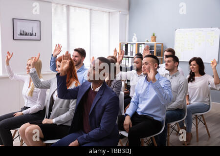 Multi-ethnische Business Leute sitzen auf Stuhl in der Zeile heben Ihre Arme im Büro Stockfoto