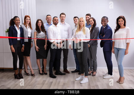 Lächelnd erfolgreiche Geschäftsfrau, die Red Ribbon mit Ihrem Personal Stockfoto