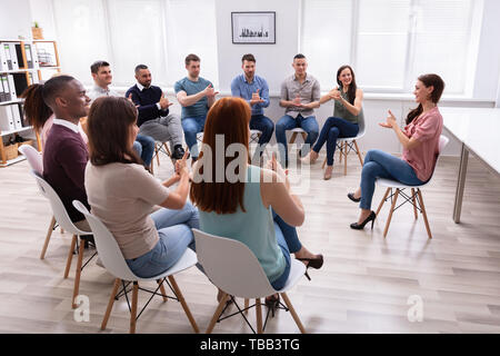 Gruppe von Jugendlichen lernen Gehörlose Geste Zeichen von Frau sitzt auf Stuhl Stockfoto