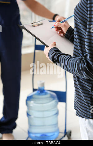 Frau mit Zwischenablage erhalten Wasser aus Kurier im Büro Stockfoto