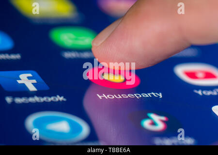 Finger, mit dem ein Symbol auf einem Smartphone oder Tablet-PC Touchscreen die Houseparty social media App zu laden. House party Anwendung. Stockfoto