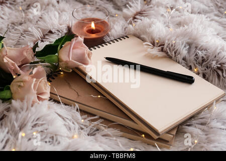 Notebook, Kerze und Blumen auf weiches Plaid Stockfoto