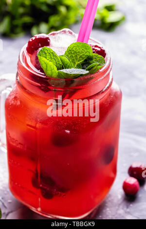 Iced hausgemachte Limonade mit Preiselbeeren, Zitrusfrüchte und frischer Minze Blatt in einem Cocktail Glas mit Strohhalm Stockfoto