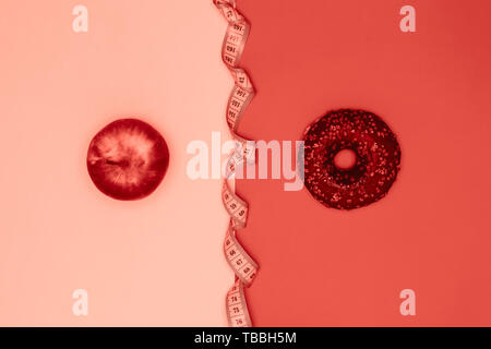 Gesundes Essen vs schädlichen Snacks. Wahl Konzept. Apple, Donut und Maßband. Lebende Korallen flach Stockfoto