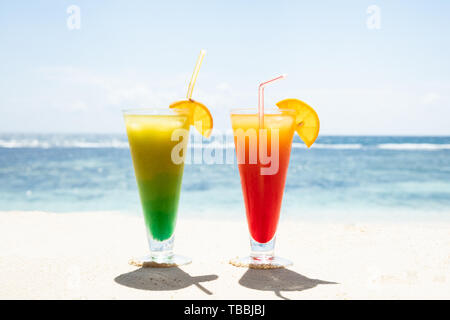 Gläser Saft in der Nähe des Meeres auf dem sandigen Strand im Sommer Stockfoto