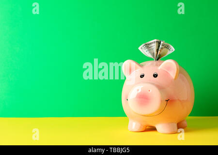 Happy Sparschwein mit hundert Dollar auf Farbe Tabelle gegen grünen Hintergrund, Platz für Text. Finanzen, Geld sparen Stockfoto