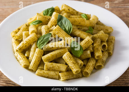 Penne Pasta mit Pesto und Basilikum auf einem Schild auf hölzernen Tisch Stockfoto