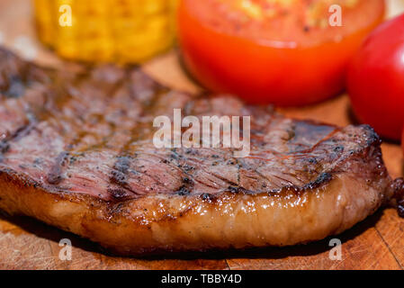 In der Nähe von frisch gegrilltes Steak auf Holz mit Tomaten und Mais Stockfoto