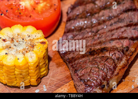 In der Nähe von frisch gegrilltes Steak auf Holz mit Tomaten und Mais Stockfoto