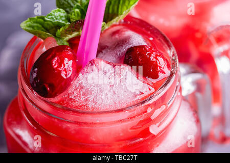 Iced hausgemachte Limonade mit Preiselbeeren, Zitrusfrüchte und frischer Minze Blatt in einem Cocktail Glas mit Strohhalm Stockfoto