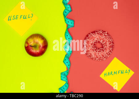 Gesundes Essen vs schädlichen Snacks. Wahl Konzept. Apple, Donut und Maßband. Lebende Korallen flach Stockfoto