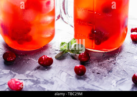 Iced hausgemachte Limonade mit Preiselbeeren, Zitrusfrüchte und frischer Minze Blatt in einem Cocktail Glas mit Strohhalm Stockfoto