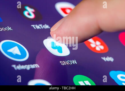 Finger, mit dem ein Symbol auf einem Smartphone oder Tablet-PC Touchscreen der Schnee Kamera App zu laden, ein Bild des Messaging und Multimedia Anwendung für soziale Medien. Stockfoto