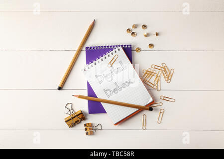 Text DIGITAL DETOX in Notebook mit Schreibwaren auf weißem Tabelle geschrieben Stockfoto