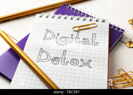 Text DIGITAL DETOX in Notebook mit Schreibwaren auf weißem Tabelle geschrieben Stockfoto